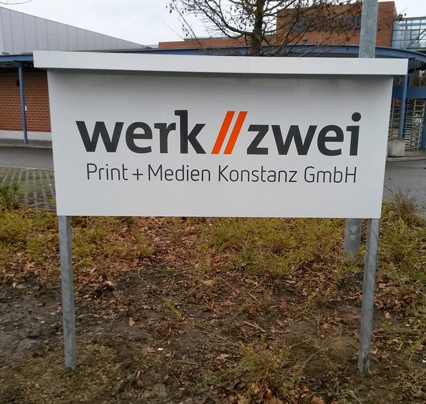 Montiertes Aluminiumschild mit beleuchtetem Schildständer bei Tageslicht